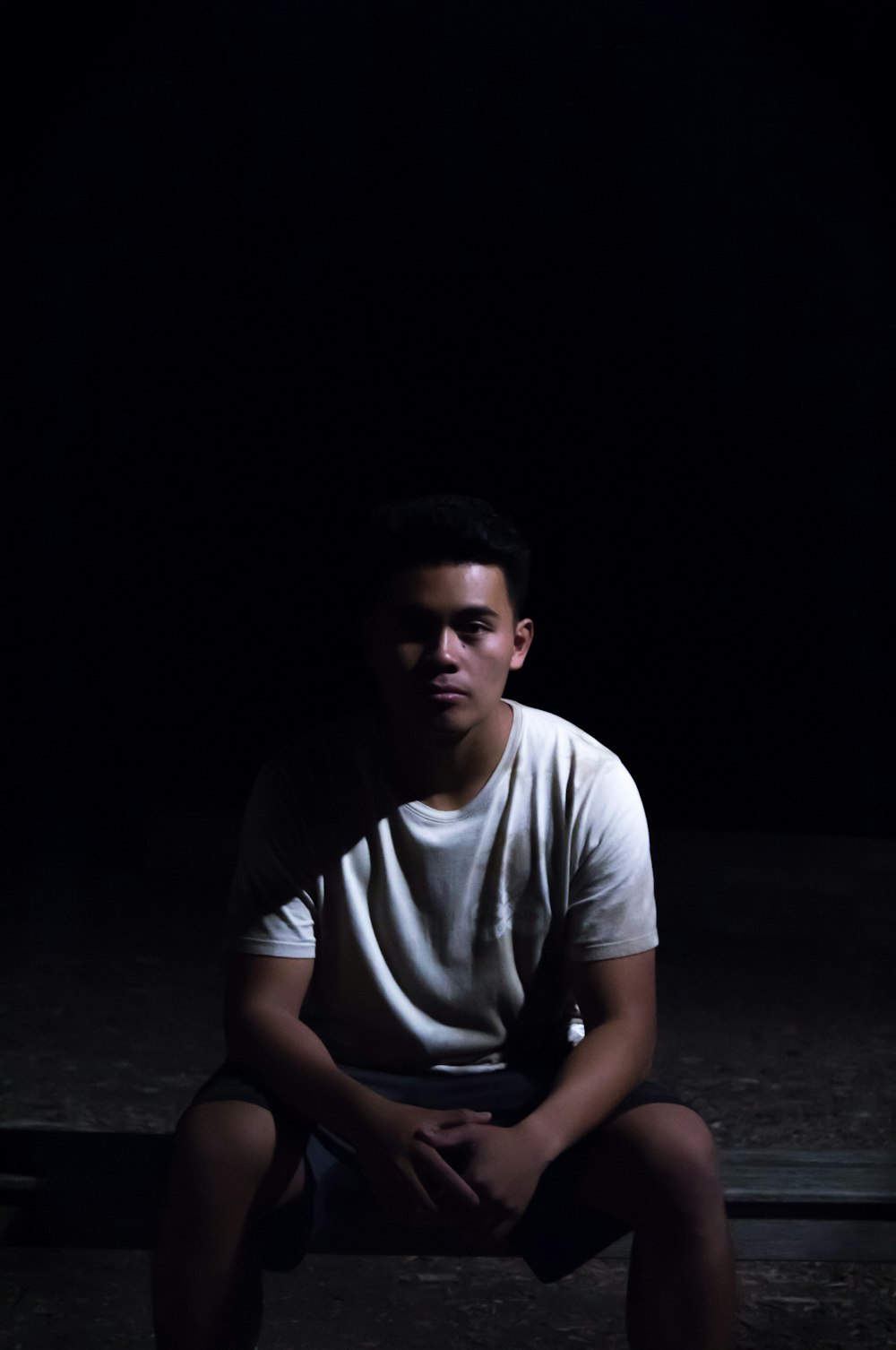 man sitting on ground with black background