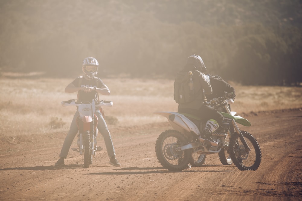 three men in motocross dirt bikes on road