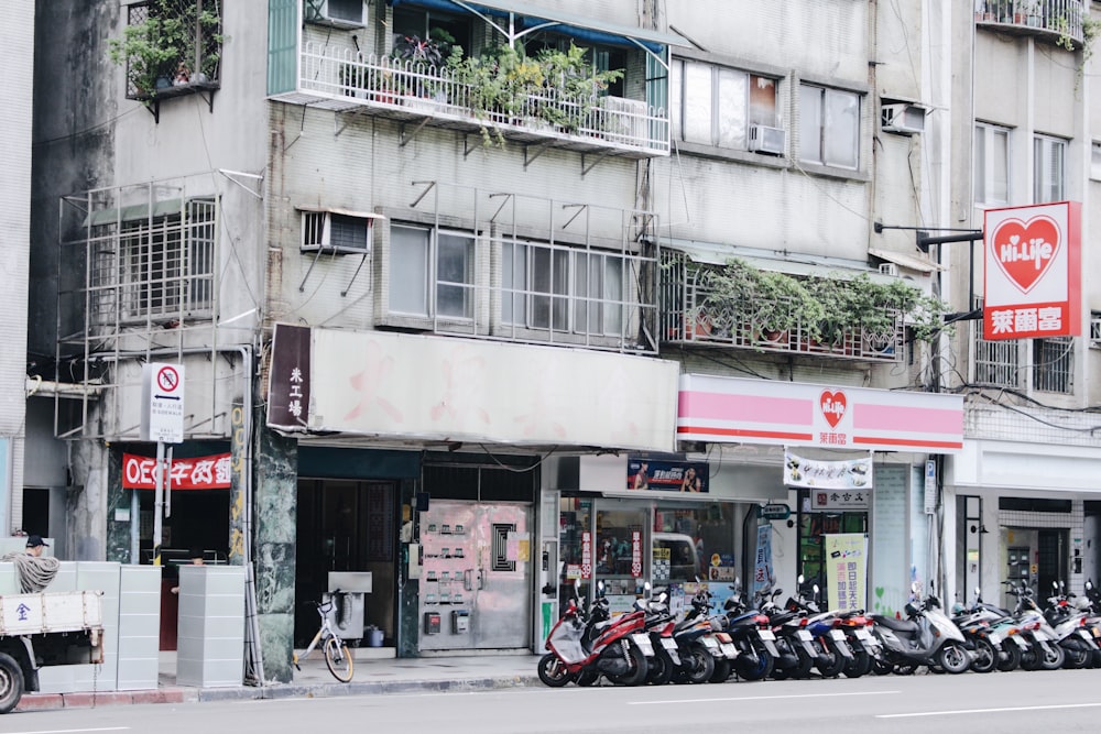 昼間は灰色のコンクリートの建物の前にバイクが停車