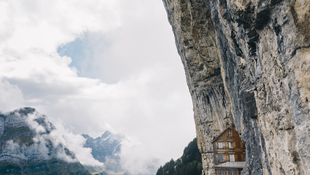 Braunes Holzhaus auf dem Gipfel des Berges unter weißem Himmel während des Tages