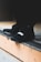 A close-up view of black athletic shoes with a visible brand logo, placed on a concrete step. The shoes are stylishly designed and appear to be suitable for sports or casual wear. The background is blurred, focusing attention on the footwear.