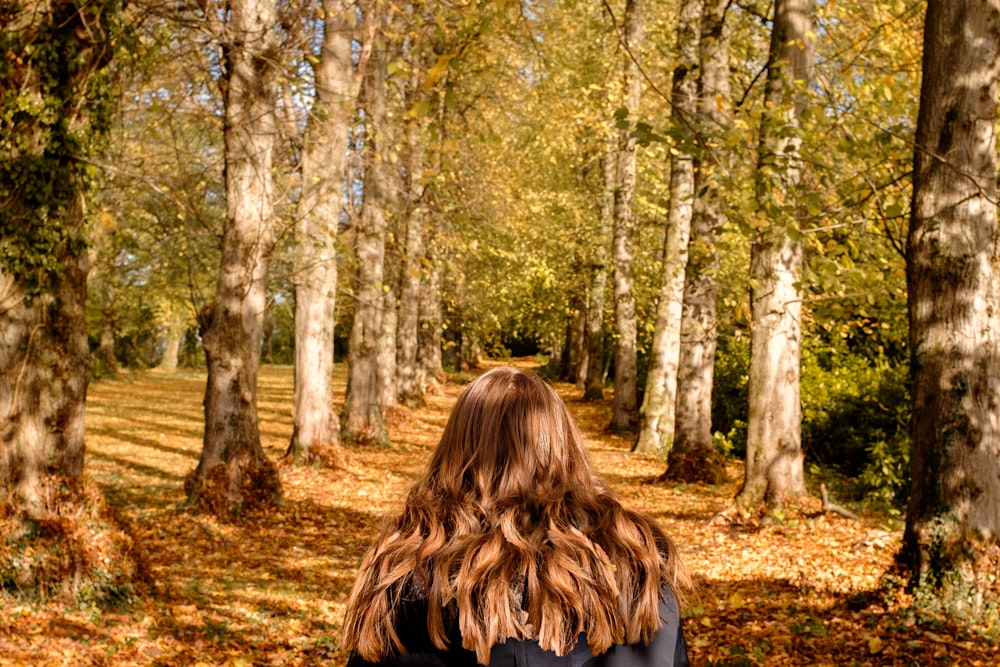 donna che cammina nel mezzo del sentiero con gli alberi