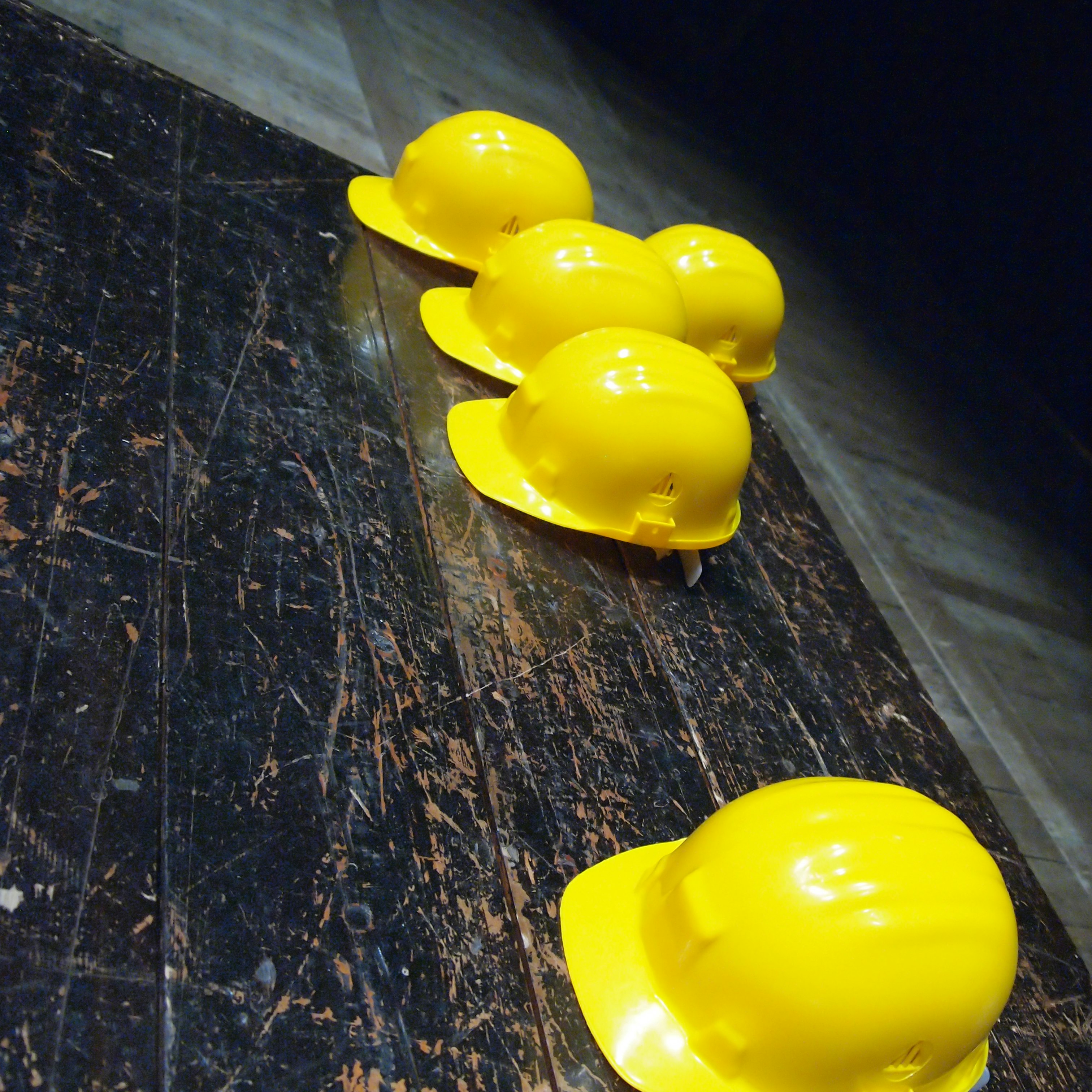 five yellow hard hats on gray surface