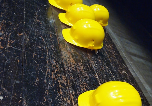 five yellow hard hats on gray surface