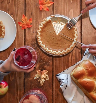 person slicing pie beside bread