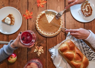 person slicing pie beside bread