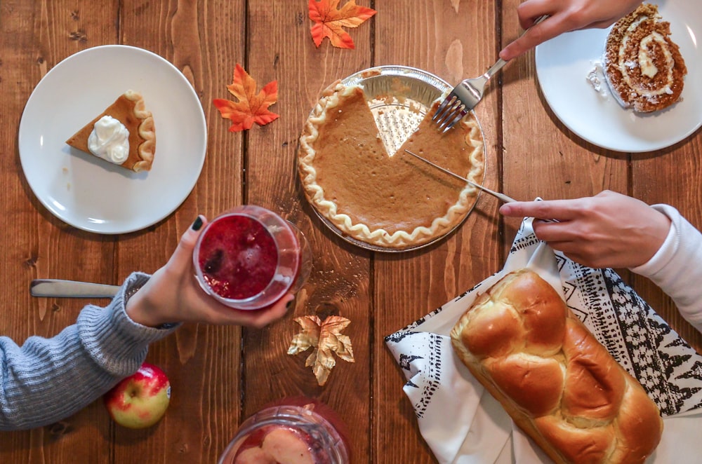 person slicing pie beside bread