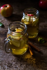 two drinking glasses filled with apple juice