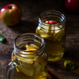 two drinking glasses filled with apple juice