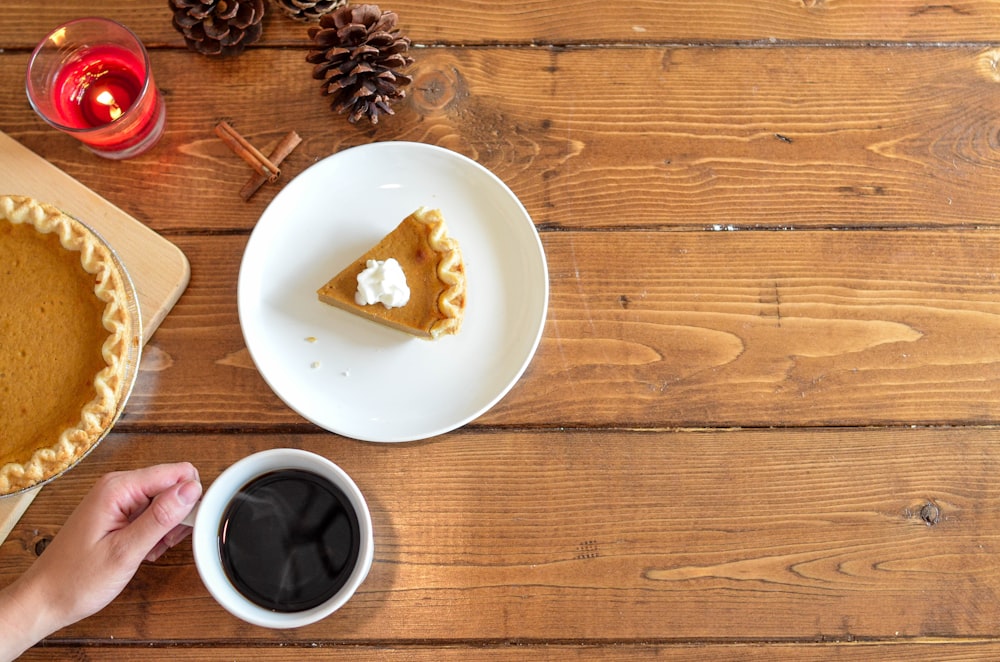 Stück Kuchen mit Schlagsahne auf Keramikteller in der Nähe von Kaffee