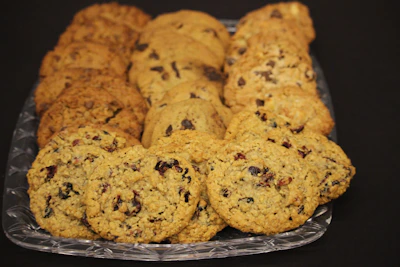 Colorful assortment of oat cookies with nuts, chocolate chips, and dried berries arranged invitingly on a ceramic plate