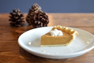 Close-up of a rustic pumpkin pie with a flaky crust and whipped cream.