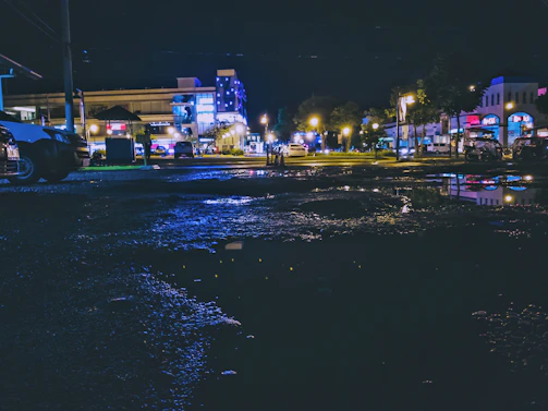 Urban night scene with sharp contrasts and reflections on wet pavement.