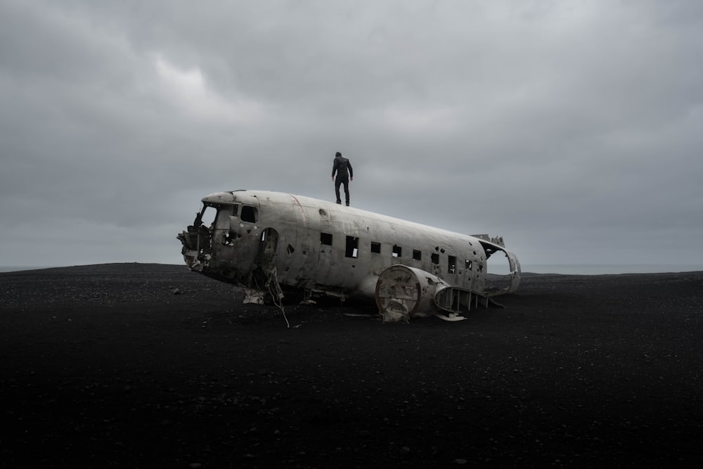 personne debout sur l’épave d’un avion sous un ciel sombre