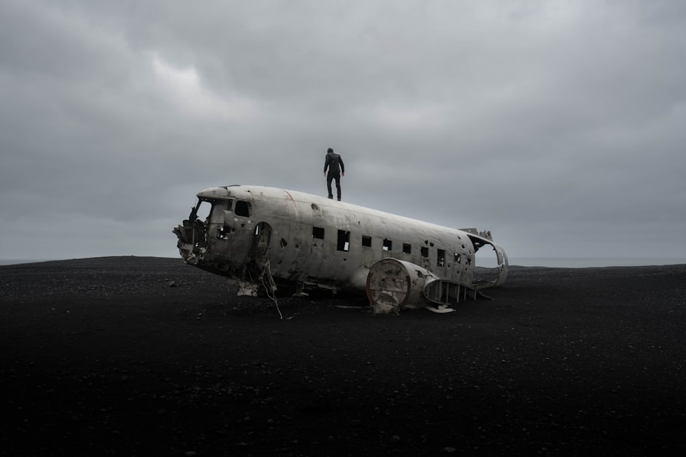 person standing on wrecked airplane under gloomy sky
