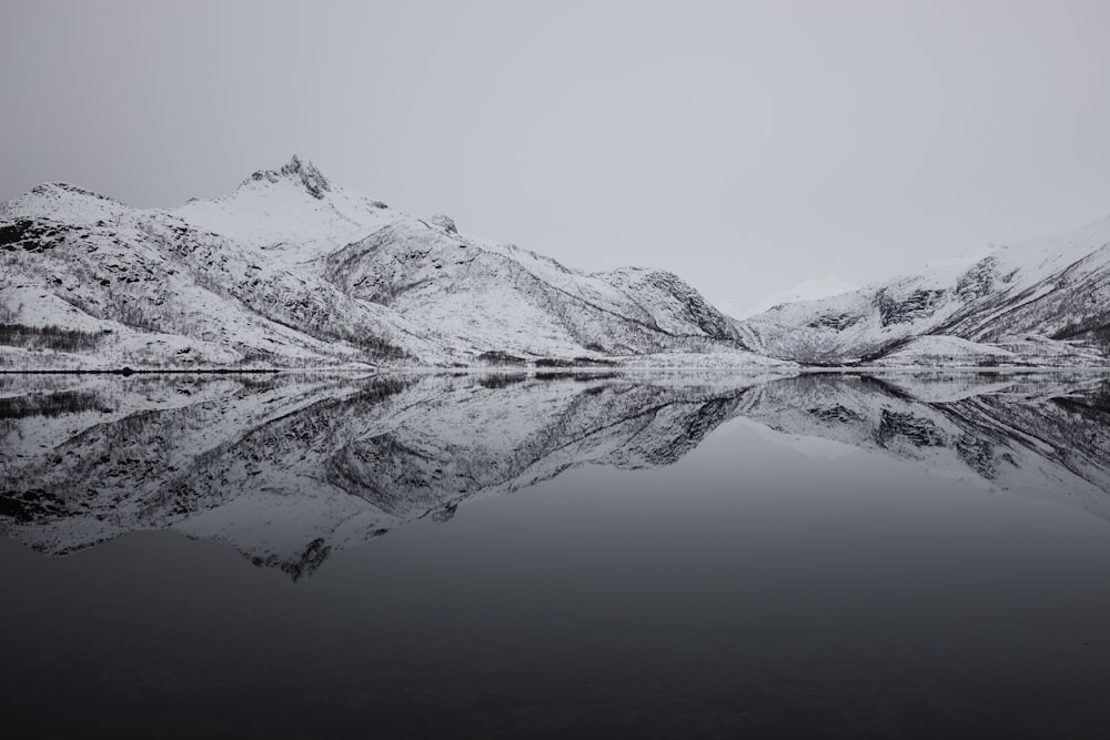 black and white mountain filled with snow near lake