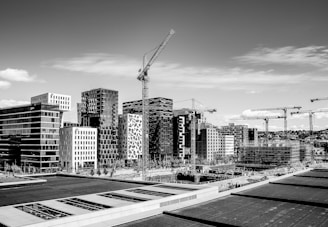 grayscale photography of tower crane on street near buildings