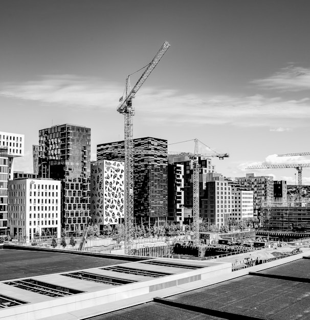 grayscale photography of tower crane on street near buildings