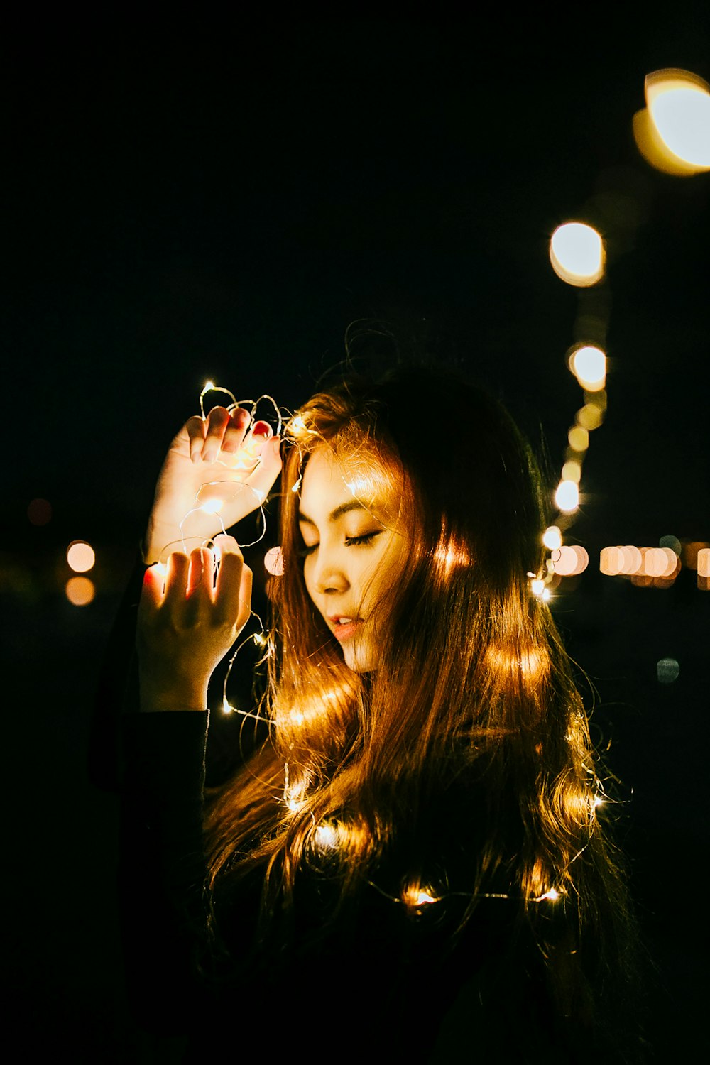 bokeh photography of woman holding string lights