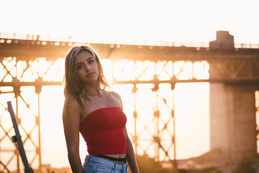 woman in red tube top standing in front of bridge