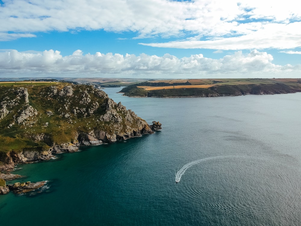 bird's-eye view photo of calm body of water with landscape field in between