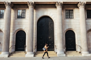 woman walking in-front of white building with ionic pillars