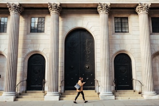 woman walking in-front of white building with ionic pillars