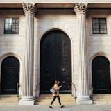 woman walking in-front of white building with ionic pillars