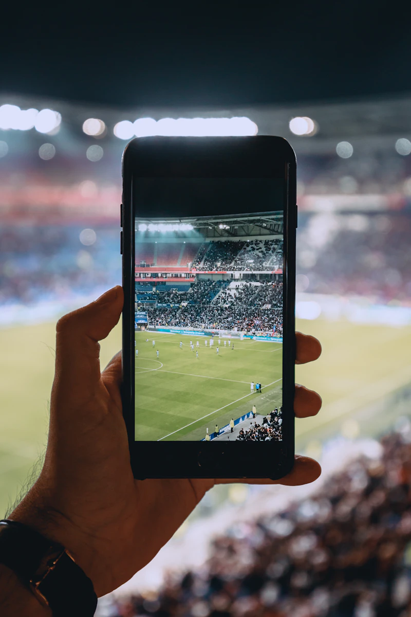 Persona revisando su celular junto a una cancha de fútbol