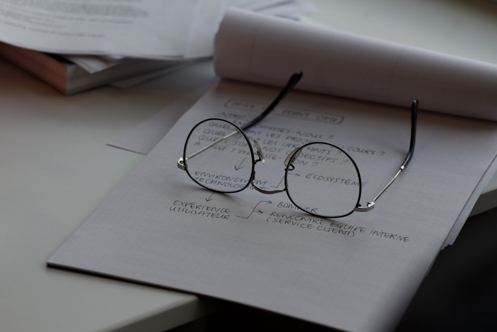 black framed eyeglasses on top of white printing paper