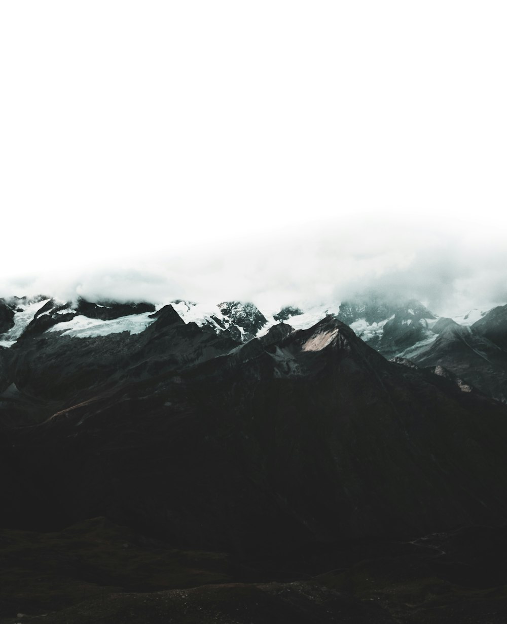 mountain range covered with snow and clouds at daytime