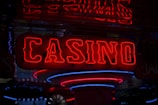 Neon lights display the word 'CASINO' in bright red, standing out against a dark background. The vibrant glow reflects a lively and bustling atmosphere.