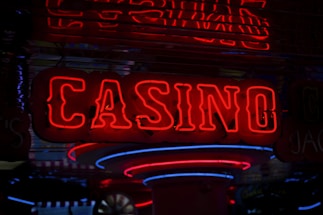 Neon lights display the word 'CASINO' in bright red, standing out against a dark background. The vibrant glow reflects a lively and bustling atmosphere.
