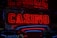 Neon lights display the word 'CASINO' in bright red, standing out against a dark background. The vibrant glow reflects a lively and bustling atmosphere.