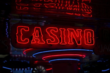 Neon lights display the word 'CASINO' in bright red, standing out against a dark background. The vibrant glow reflects a lively and bustling atmosphere.