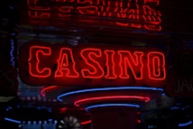 Neon lights display the word 'CASINO' in bright red, standing out against a dark background. The vibrant glow reflects a lively and bustling atmosphere.