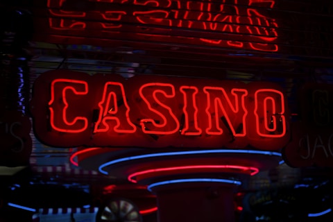Neon lights display the word 'CASINO' in bright red, standing out against a dark background. The vibrant glow reflects a lively and bustling atmosphere.