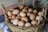 A close-up of fresh eggs in a rustic basket on a wooden table.