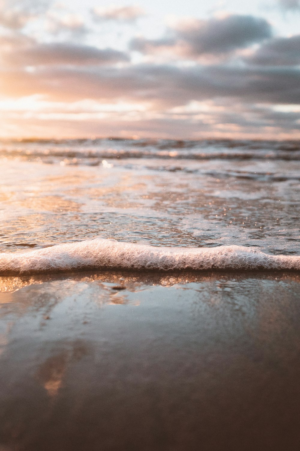 selective focus photo of water waves on sand