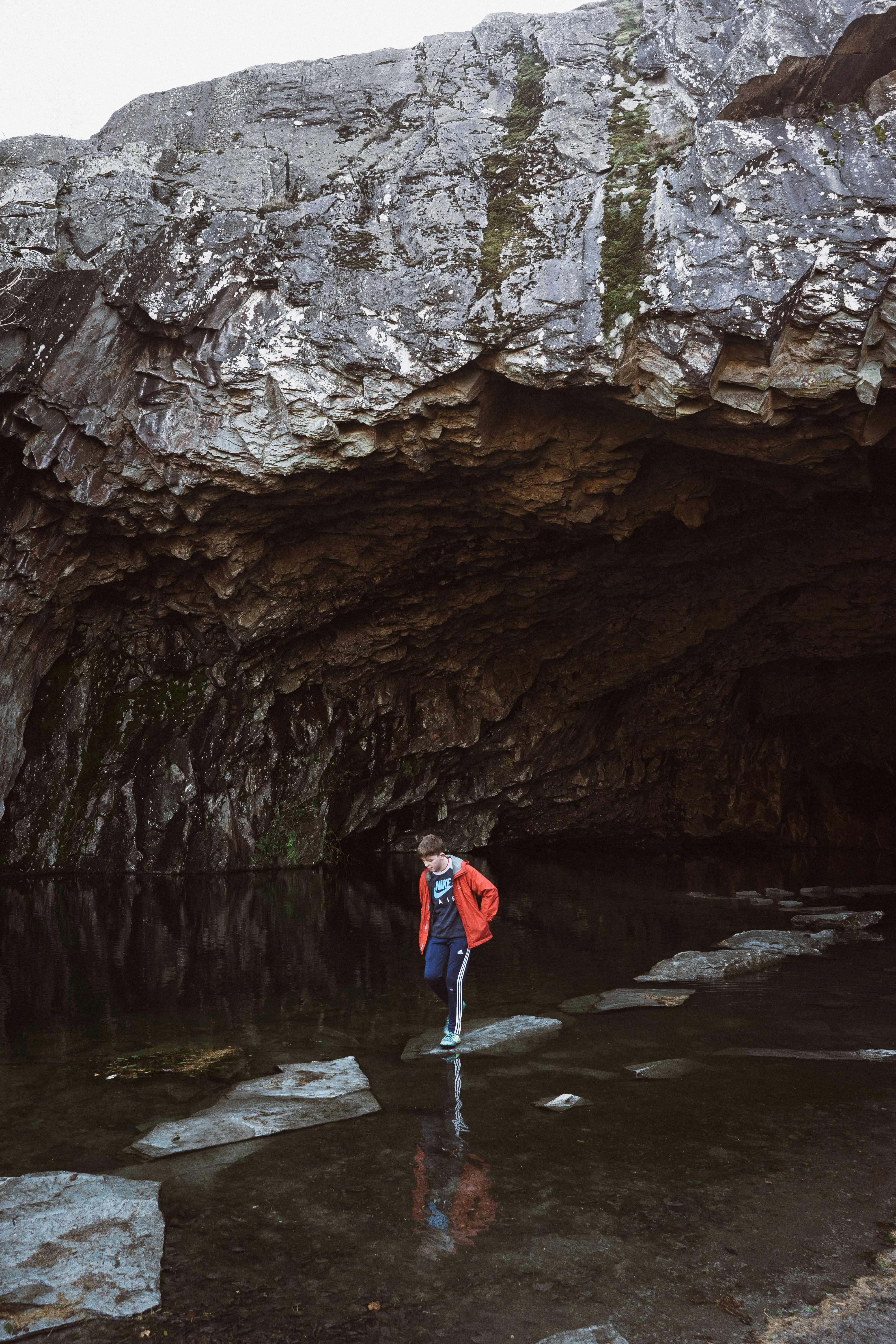 man stepping on stone near cave