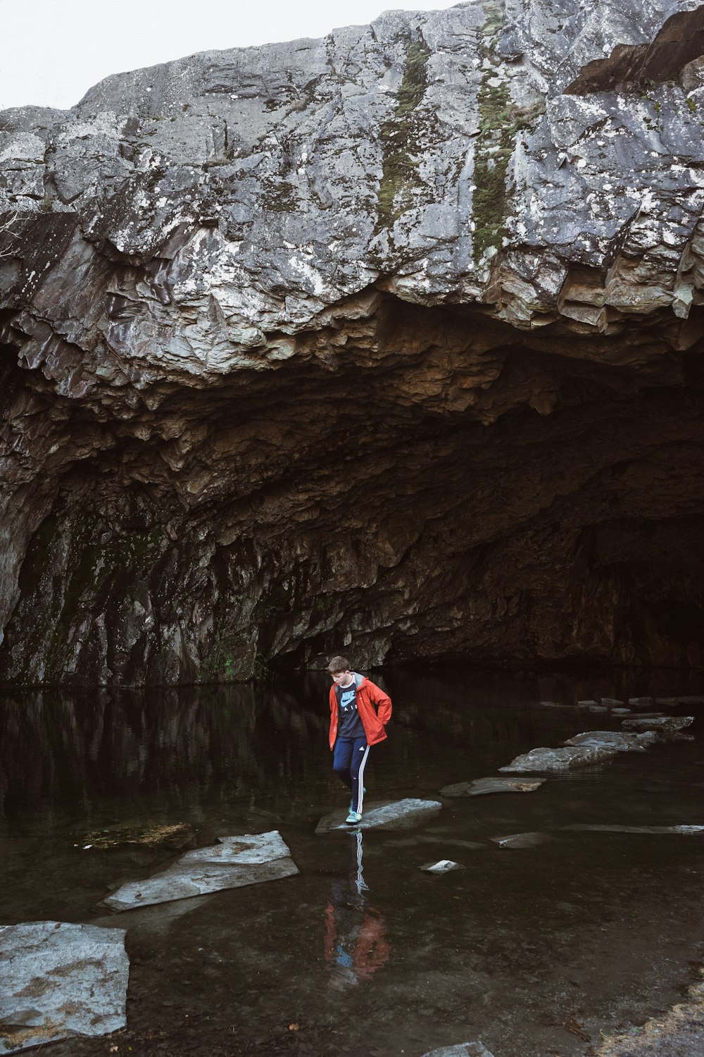 man stepping on stone near cave