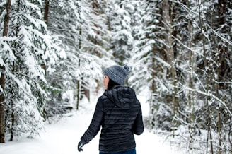 A winter scene showing a person wearing a sleek elseason jacket walking through frosted trees.