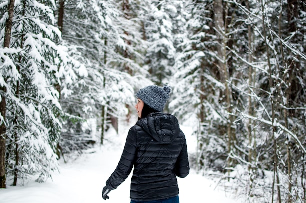 A winter scene showing a person wearing a sleek elseason jacket walking through frosted trees.