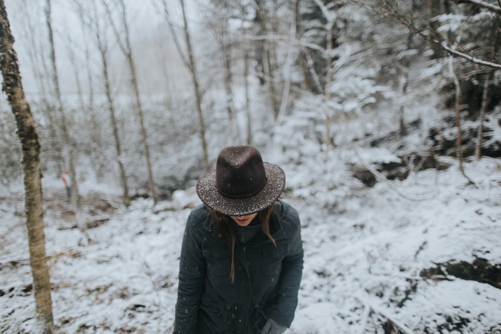 personne portant un manteau noir et un chapeau brun