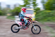 An action shot of a biker speeding on a dusty trail wearing full tactical gear.