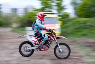 An action shot of a biker speeding on a dusty trail wearing full tactical gear.