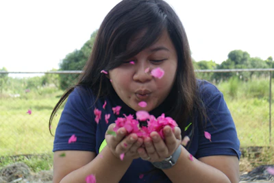 Close-up of gentle hands releasing flower petals into a flowing stream.