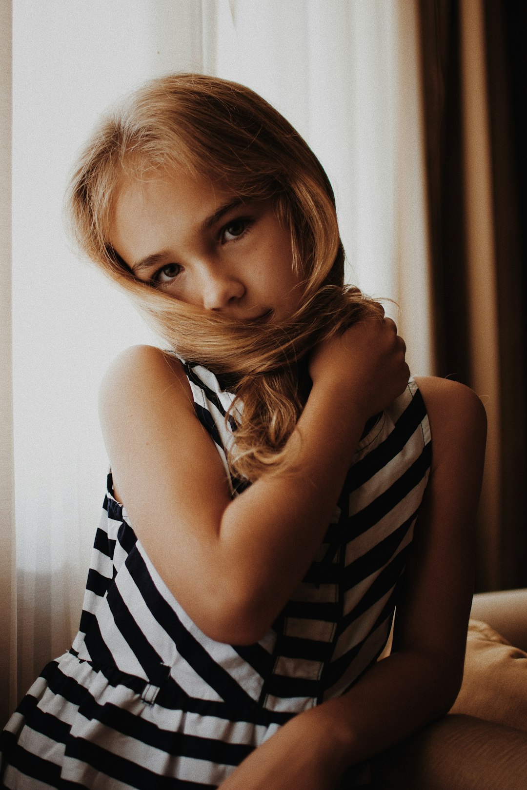 girl's holding her hair beside window