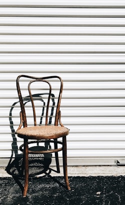 brown wooden chair beside white wall