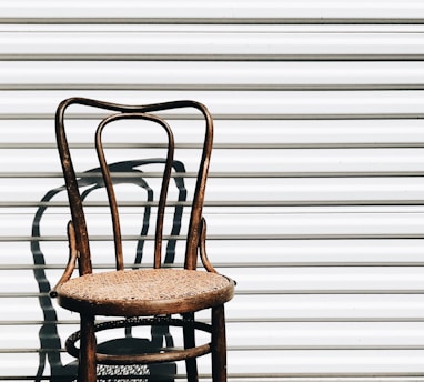 brown wooden chair beside white wall